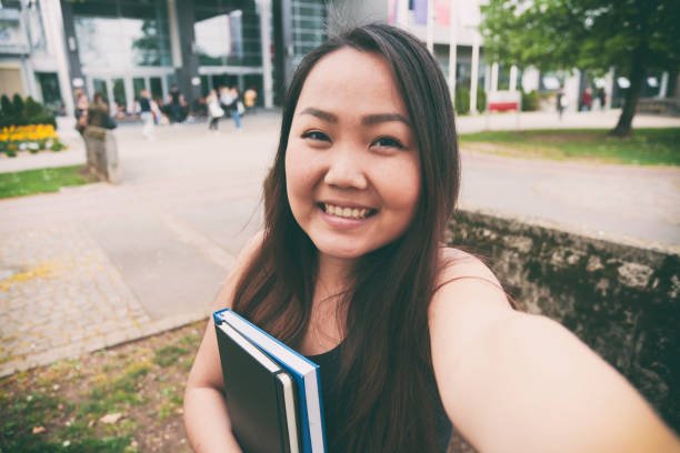 Female student taking a selfie on university grounds. Mongolian or asian ethnicity.